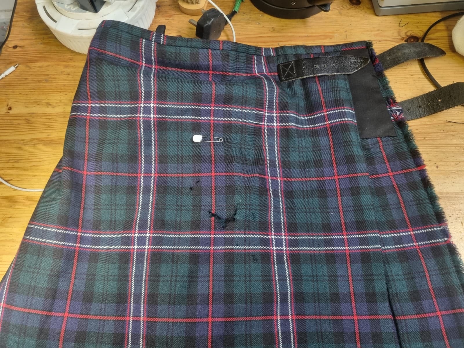 Black Watch tartan kilt apron panel with abrasion hole marked by a pin.