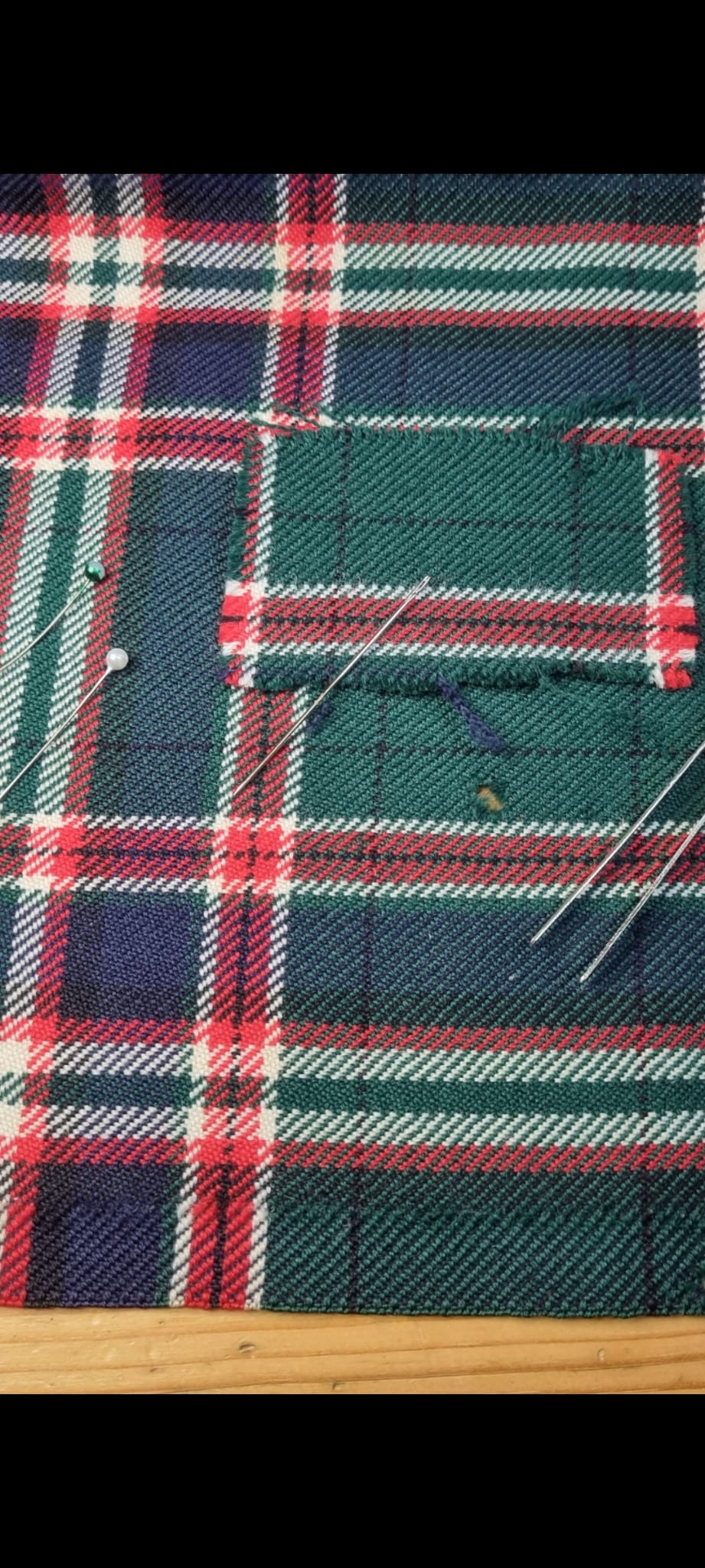 Red and green tartan kilt with a rectangular area of fabric loss and fraying.