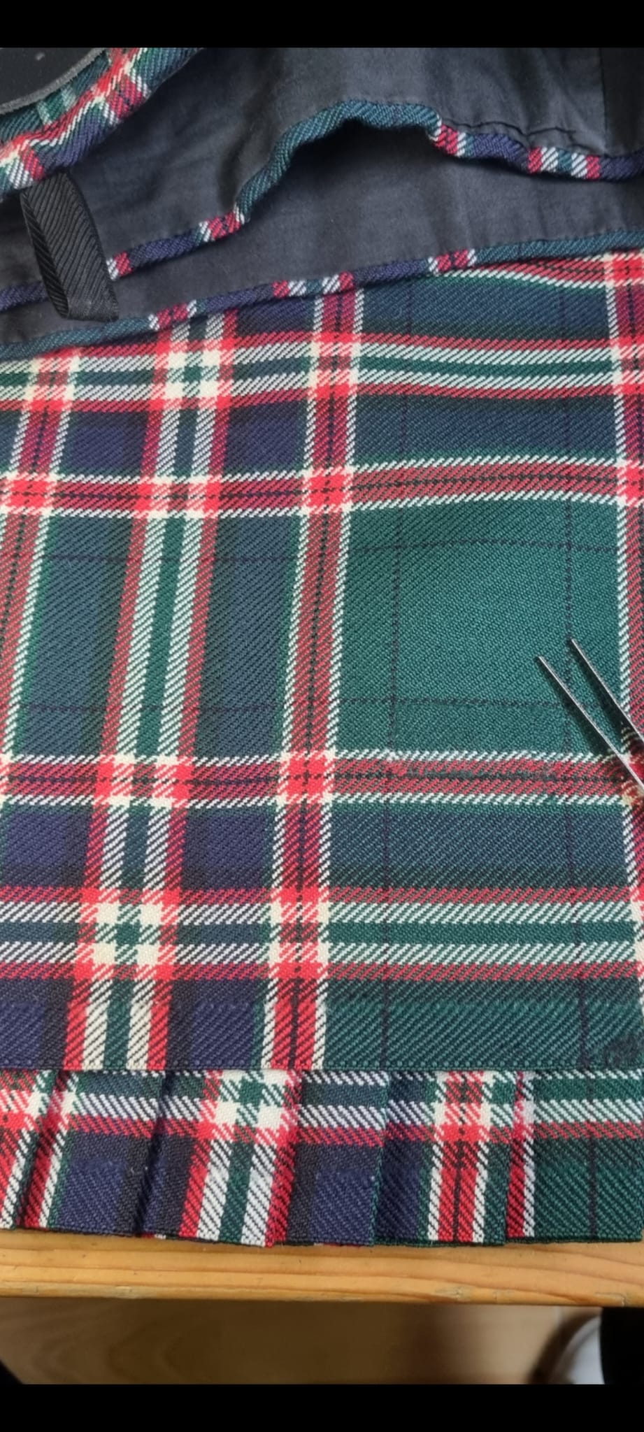 Red and green tartan kilt after sectional reweave and pattern restoration.