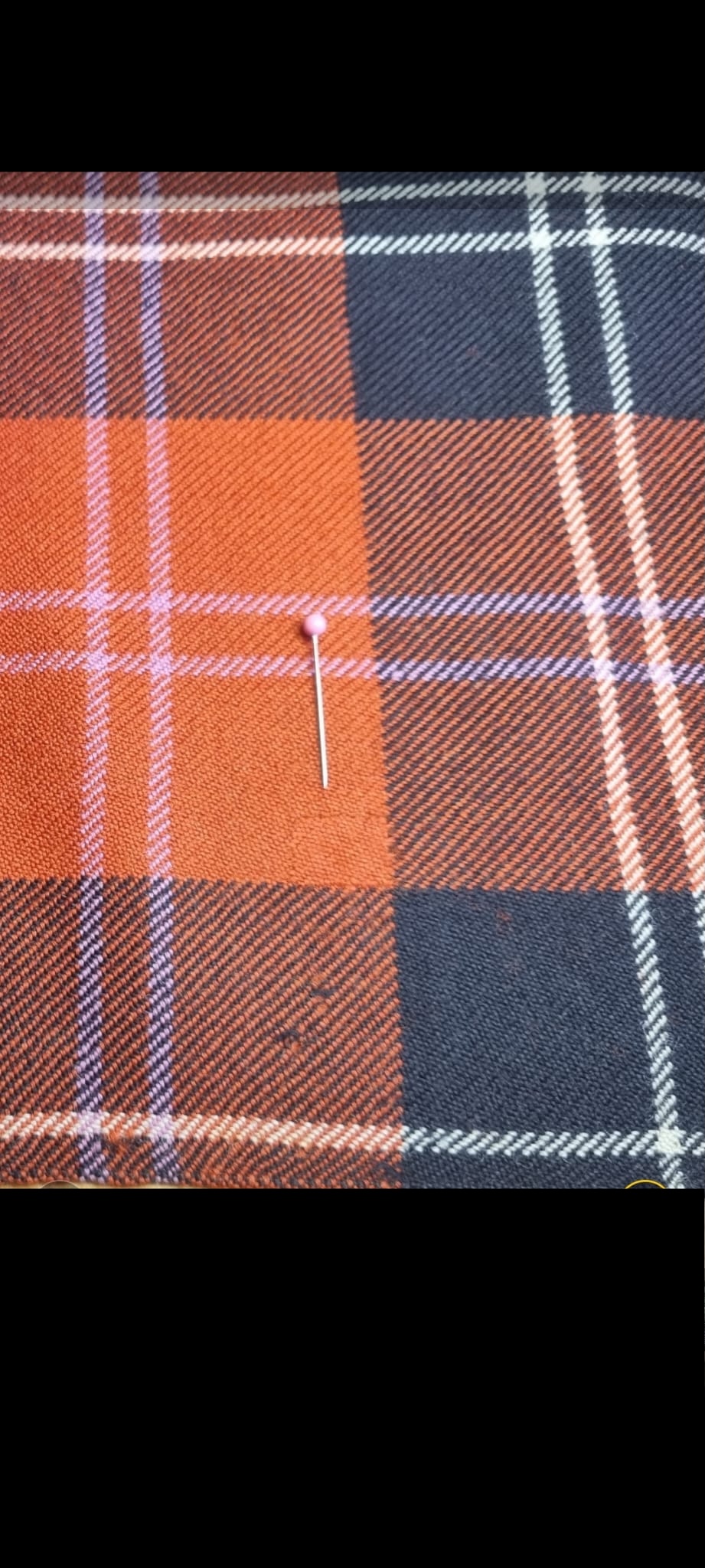 Orange and navy tartan kilt after invisible moth-hole darn and fibre restoration.